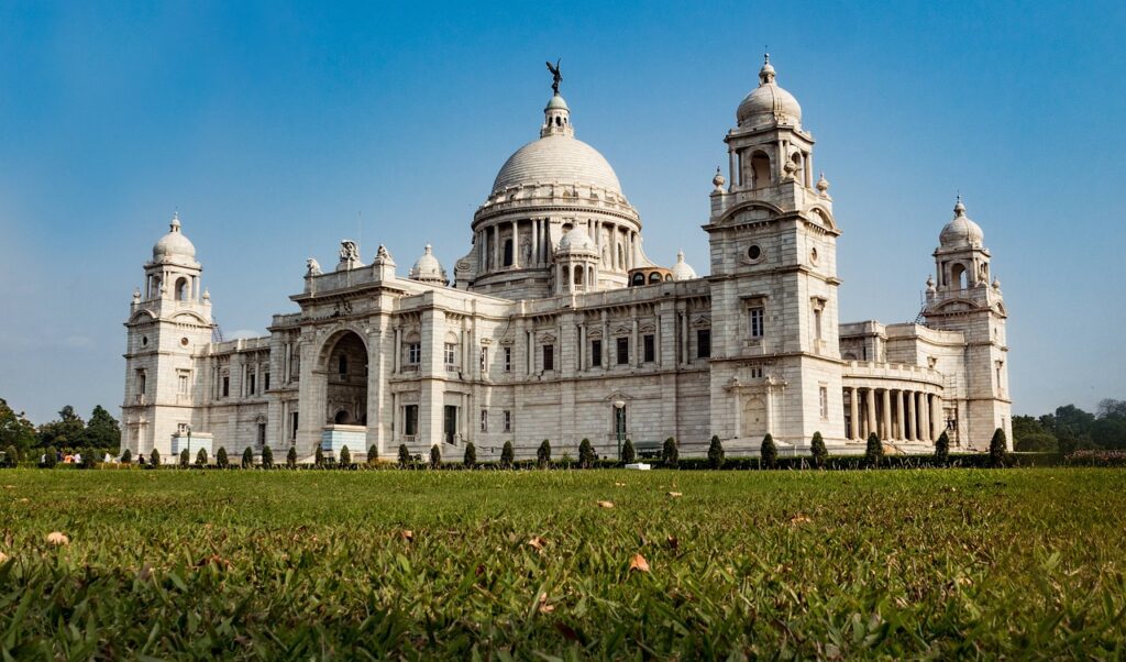 Majestic Victoria Memorial in Kolkata, surrounded by lush gardens and under a blue sky, showcasing its grand architectural beauty and historical significance