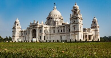 Majestic Victoria Memorial in Kolkata, surrounded by lush gardens and under a blue sky, showcasing its grand architectural beauty and historical significance